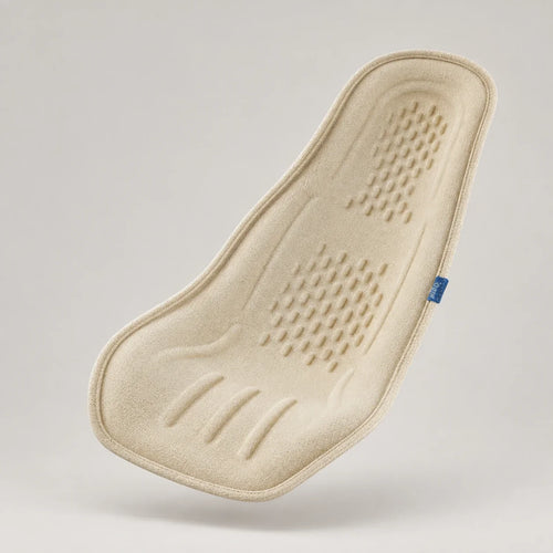 Three-quarter view of the cream Nido Pod, showing its contoured textile surface and blue woven label